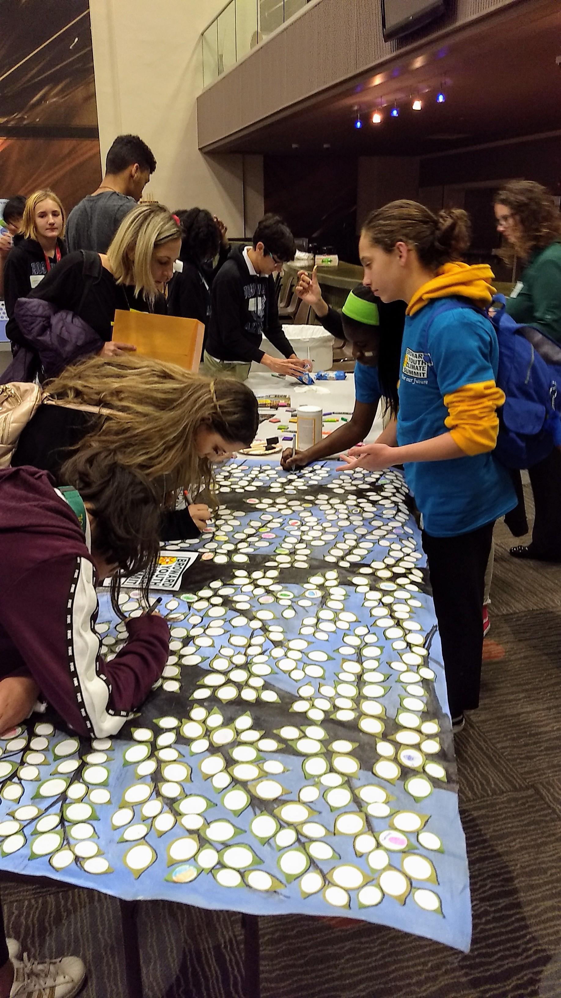 Youth Summit students signing the group art project 